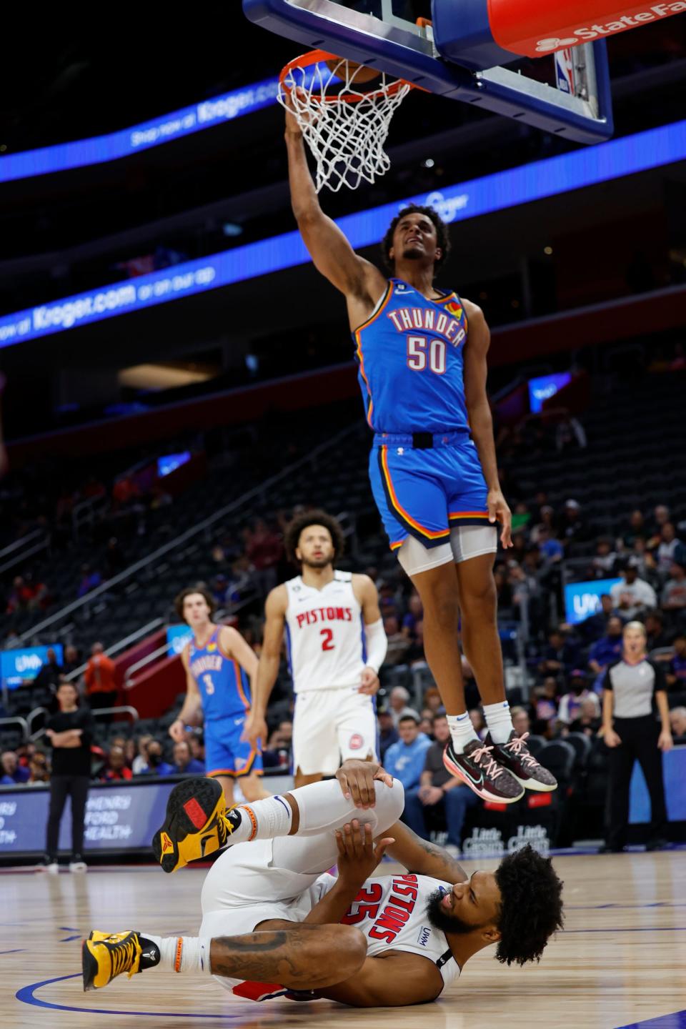 Pistons forward Marvin Bagley III grabs his knee and Thunder forward Jeremiah Robinson-Earl dunks in the first half of the preseason game on Tuesday, Oct. 11, 2022, at Little Caesars Arena.