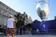 People take pictures in front of an inflatable model of the Champions League cup in Porto's central Aliados square as thousands of English fans make their way to Portugal's northern city for the League's final match and hotels and bars hope for a boost aft