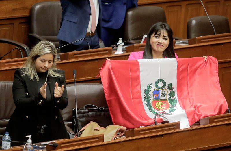 Una congresista de Perú muestra una bandera peruana después de que el Congreso aprobó la destitución del presidente Pedro Castillo, en Lima