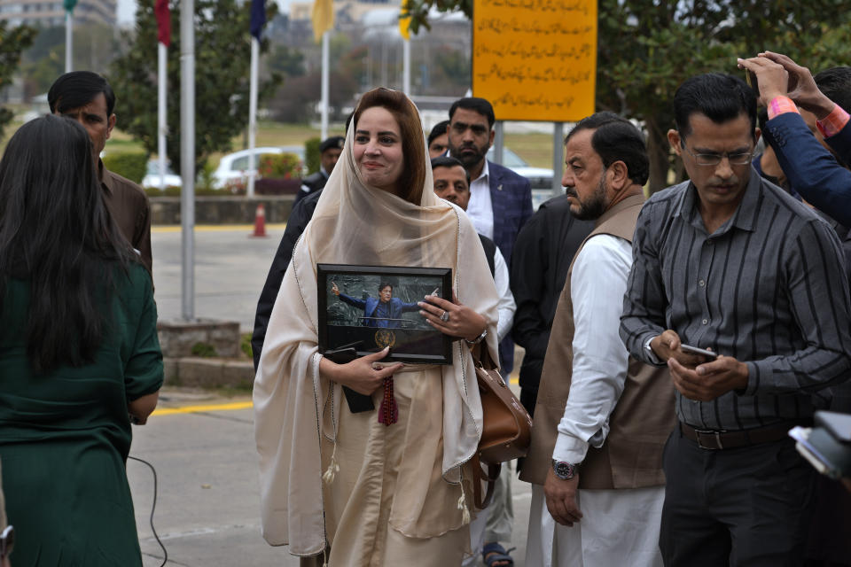 Pakistan's newly elected lawmaker Zartaj Gul, displays a picture of her leader and imprisoned former Prime Minister Imran Khan as she arrives to attend the opening session of parliament, in Islamabad, Pakistan, Thursday, Feb. 29, 2024. Pakistan's National Assembly swore in newly elected members on Thursday in a chaotic scene, as allies of jailed former Premier Khan protested what they claim was a rigged election. (AP Photo/Anjum Naveed)