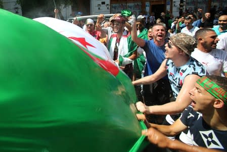 Demonstrators carry flags during a protest demanding the removal of the ruling elite in Algiers