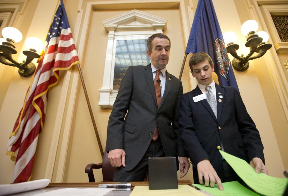 In this Jan. 26, 2016 photo Virginia Lt. Gov. and Democratic candidate for governor, Ralph Northam, left, receives papers from Senate page Jacob Ellis, of Virginia Beach, during a Senate session at the Capitol in Richmond, Va. In what sounds like an echo of 2016, governor’s races this year in Virginia and New Jersey are being swept up in many of the same political currents that emerged during last year’s turbulent presidential campaign. (AP Photo/Steve Helber)