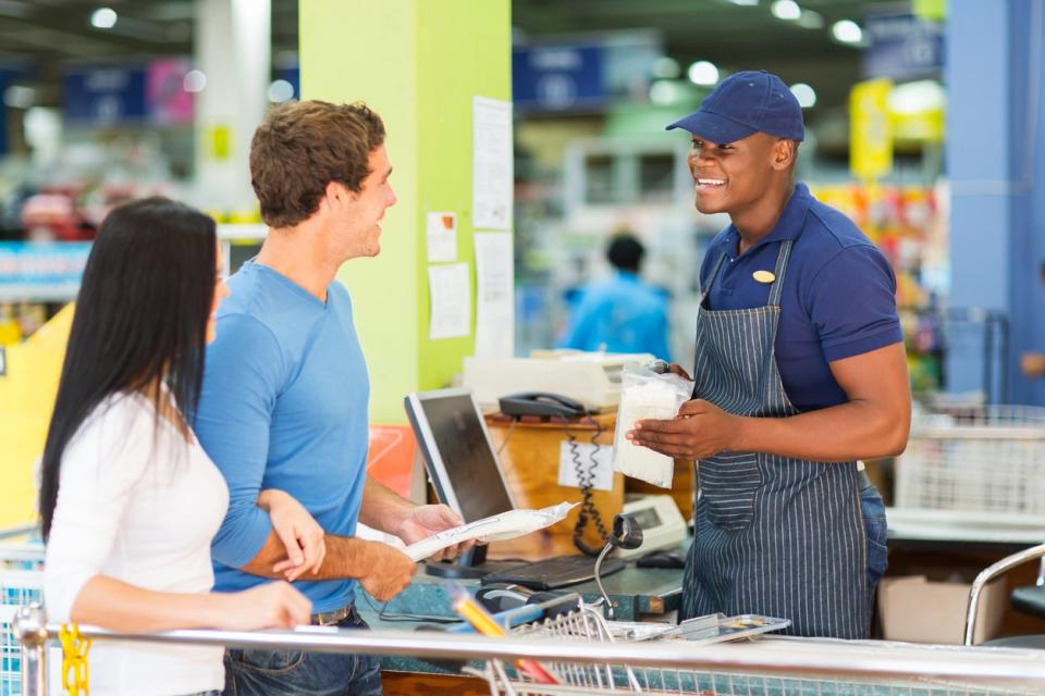 Male and female customers at the checkout counter of a retail store.