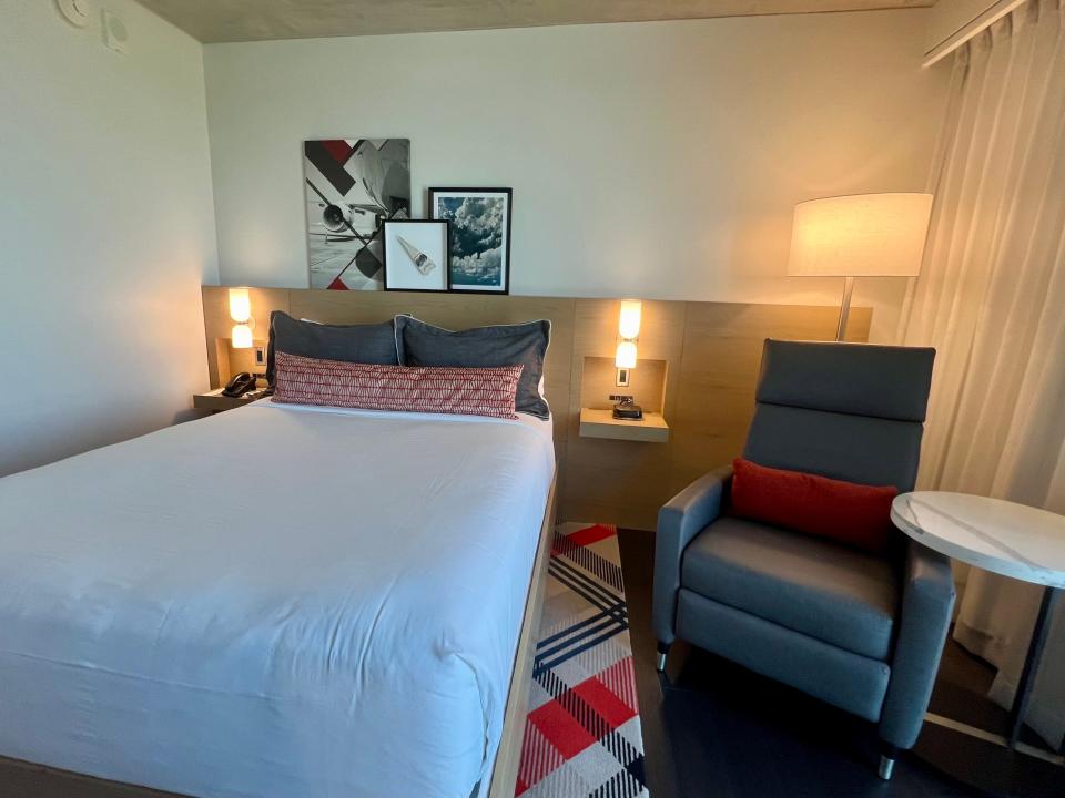 The bed and chair in the hotel room with airplane artwork on the wall behind the bed.