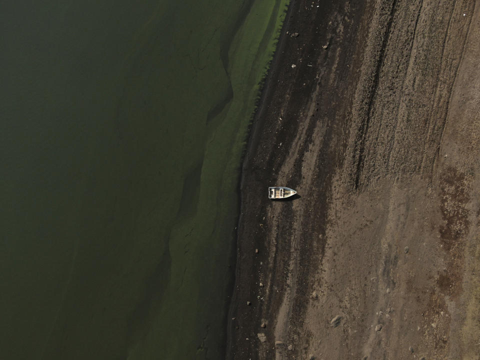 A boat sits idle on the banks of Villa Victoria Dam, the main water supply for Mexico City residents, on the outskirts of Toluca, Mexico, Thursday, April 22, 2021. The mayor of Mexico City said the drought was the worst in 30 years, and that problem can be seen at the series of reservoirs that bring in water from other states to supply the capital. (AP Photo/Fernando Llano)