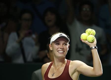 Caroline Wozniacki of Denmark prepares to hit balls to the audience after defeating Agnieszka Radwanska of Poland during their WTA Finals singles tennis match at the Singapore Indoor Stadium October 23, 2014. REUTERS/Edgar Su