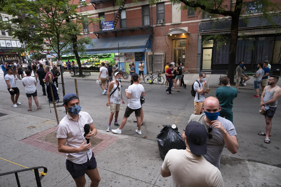 People gather on a street in the Hell's Kitchen neighborhood of New York, Friday, May 29, 2020, during the coronavirus pandemic. The street has been blocked off from traffic to allow residents to gather in open spaces with some social distancing. (AP Photo/Mark Lennihan)