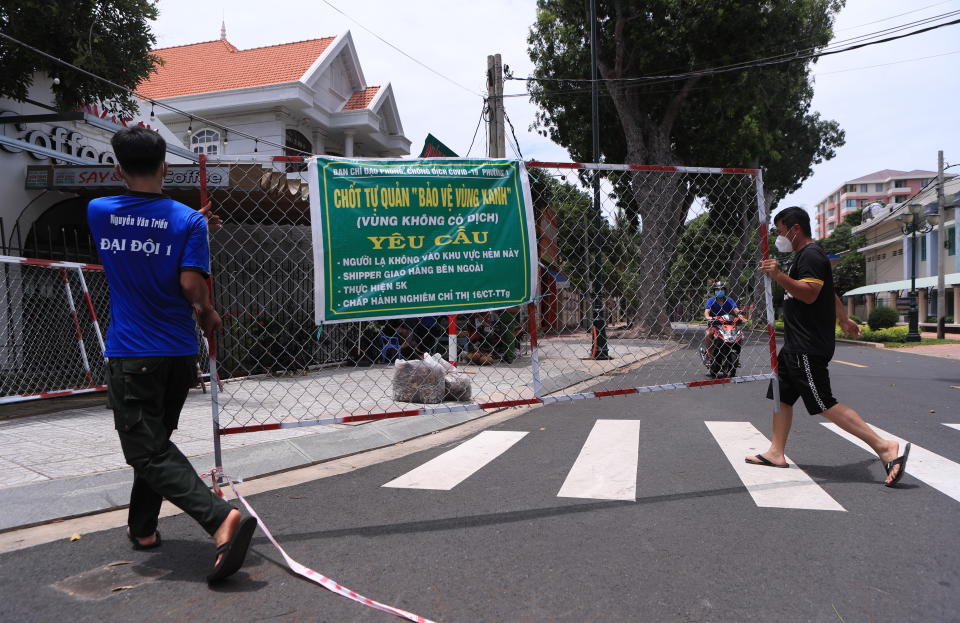 People remove a barricade in Vung Tau, Vietnam Thursday, Sept. 30, 2021. Vietnam will lift a lockdown order in its largest city on Friday, ending almost three months of strict movement restrictions to curb a coronavirus surge. (AP Photo/Hau Dinh)