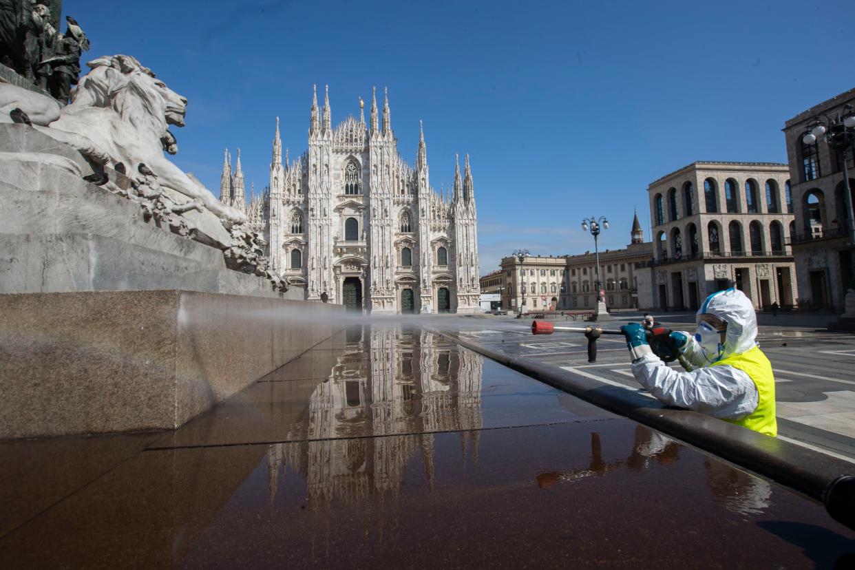 A worker sprays disinfectant to sanitize Duomo square in downtown Milan, Italy, on Tuesday, March 31, 2020.