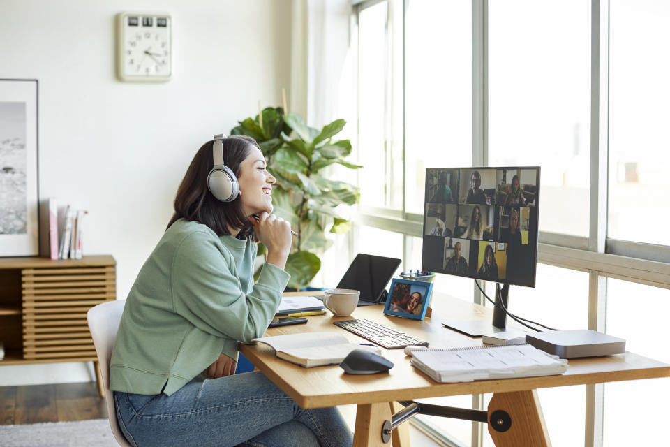 Woman with headphones smiles while on a work call