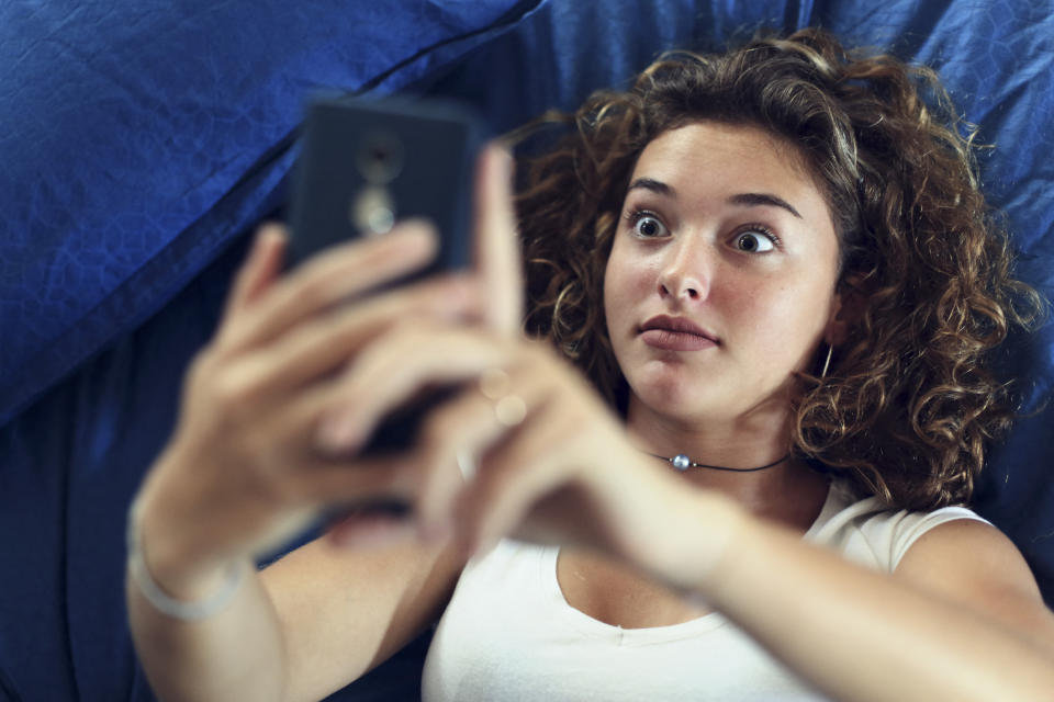 Woman looks surprised taking a selfie with a smartphone