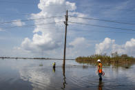 Utility crews stand in water as they work on repairing power lines along Highway 23 in Plaquemines Parish, La., over a week after Hurricane Ida on Tuesday, Sept. 7, 2021. (Chris Granger/The Times-Picayune/The New Orleans Advocate via AP)