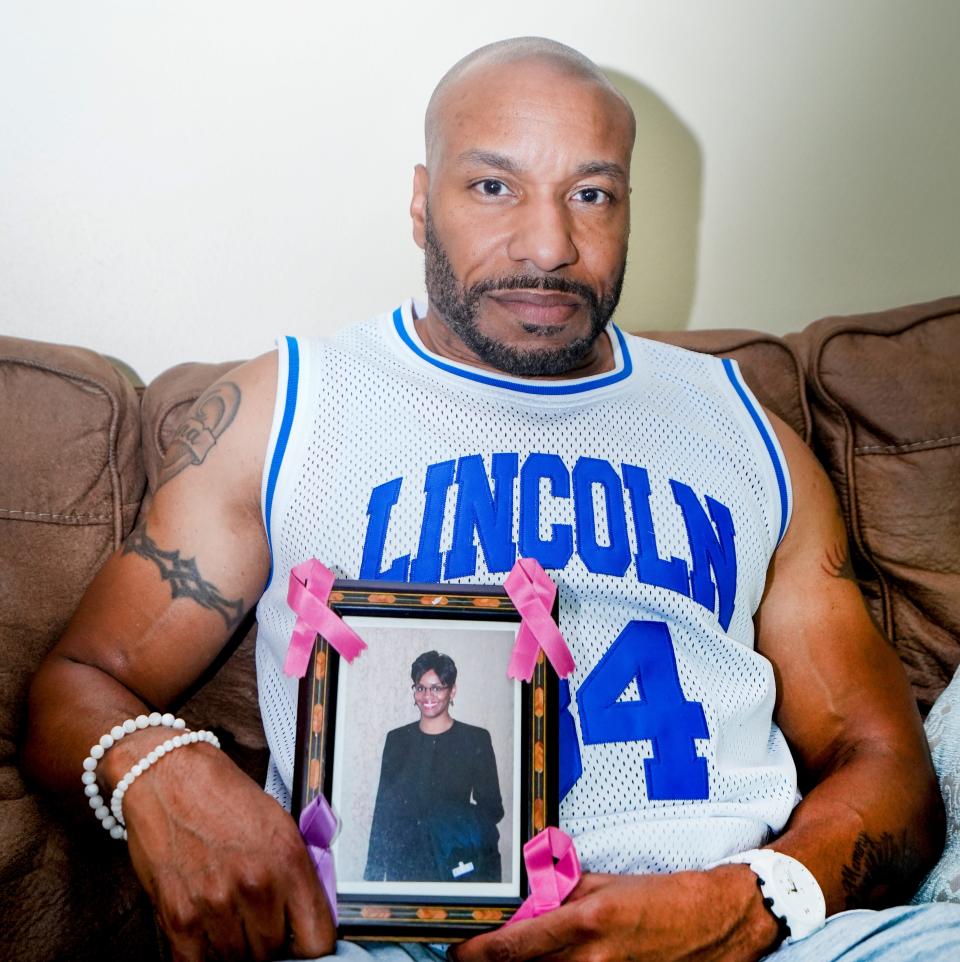 Michael Washington holds a photo of his sister, Sherida Washington Davis, who was killed in 2017.