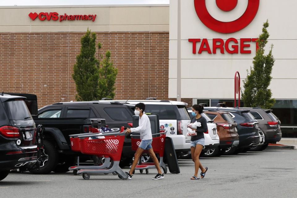 Shoppers take purchases to their vehicle in the parking lot of a Target store, Tuesday, Aug. 4, 2020, in Marlborough, Mass. (AP Photo/Bill Sikes)