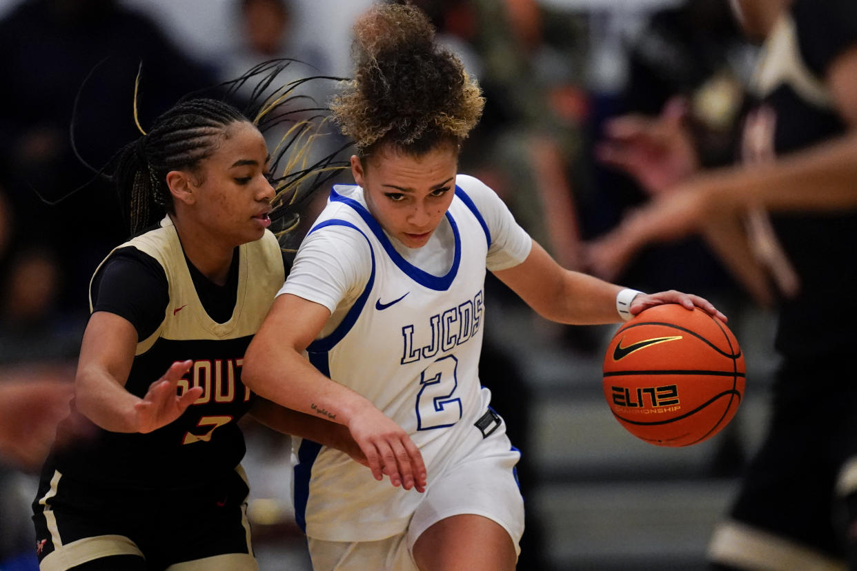 La Jolla Country Day high school point guard Jada Williams, center, drives to the basket during a basketball game Friday, Nov. 18, 2022, in Chatsworth, Calif. If there's a face of the bold new frontier of name, image and likeness (NIL) at the high school level, it might as well be the 17-year-old Williams, who is a senior point guard at San Diego's La Jolla Country Day. (AP Photo/Gregory Bull)