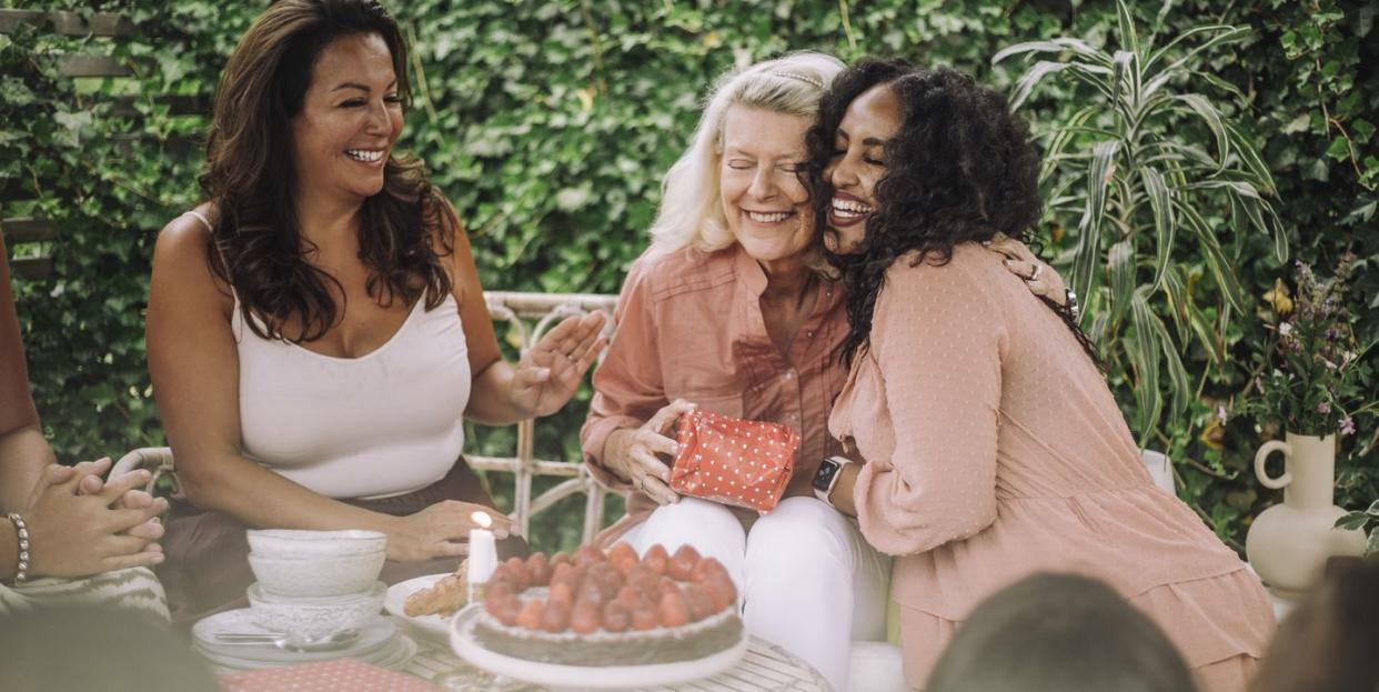 smiling daughter embracing mother in birthday party