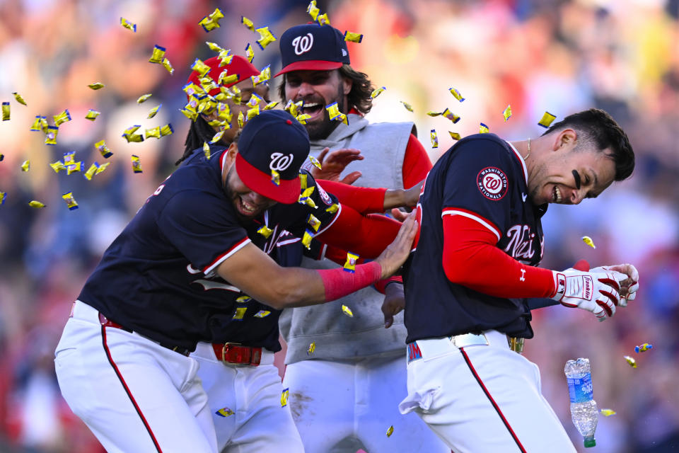 Washington Nationals' Joey Meneses, right, is showered with bubble gum and mobbed by teammates after driving in the game winning run in the 10th inning of a baseball game against the Houston Astros at Nationals Park, Saturday, April 20, 2024, in Washington. (AP Photo/John McDonnell)