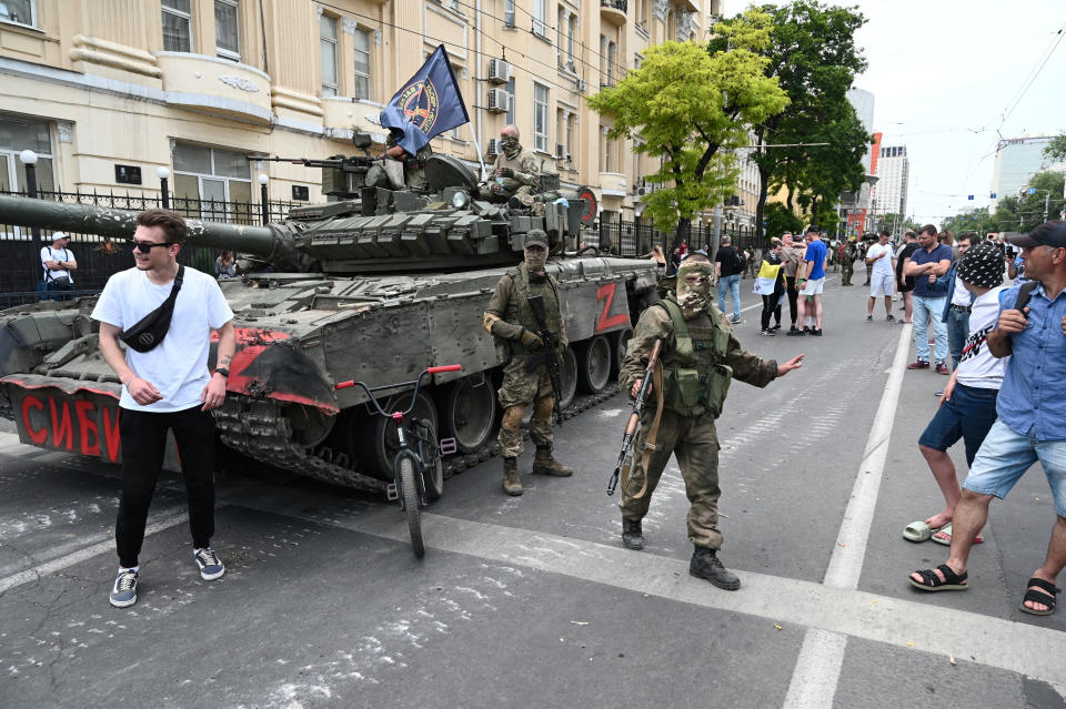 Civilians gather in a street around a tank marked 