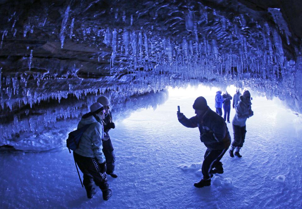 In this Feb. 2, 2014 photo people take pictures of each other in a cave at Apostle Islands National Lakeshore in northern Wisconsin, transformed into a dazzling display of ice sculptures by the arctic siege gripping the Upper Midwest. The caves are usually are accessible only by water, but Lake Superior’s rock-solid ice cover is letting people walk to them for the first time since 2009. (AP Photo/The Minneapolis Star Tribune, Brian Peterson) MANDATORY CREDIT; ST. PAUL PIONEER PRESS OUT; MAGS OUT; TWIN CITIES TV OUT