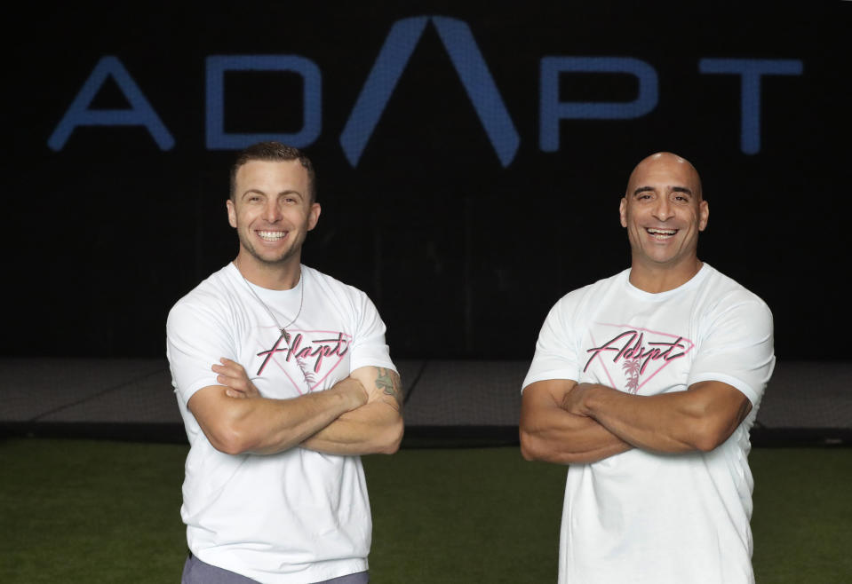 In this Thursday, June 4, 2020 photo, ADAPT gym owners Scott Grondin, left, and Jorge Sanchez pose for a photo at the gym in North Miami, Fla. The business partners and co-founders of the gym just got the OK to reopen their Miami area studio Monday after three months. Desperate to keep their carefully built 15-person team, they gave up their own salaries to keep the entire staff at full pay, relying on them to quickly pivot to online fitness training. (AP Photo/Wilfredo Lee)