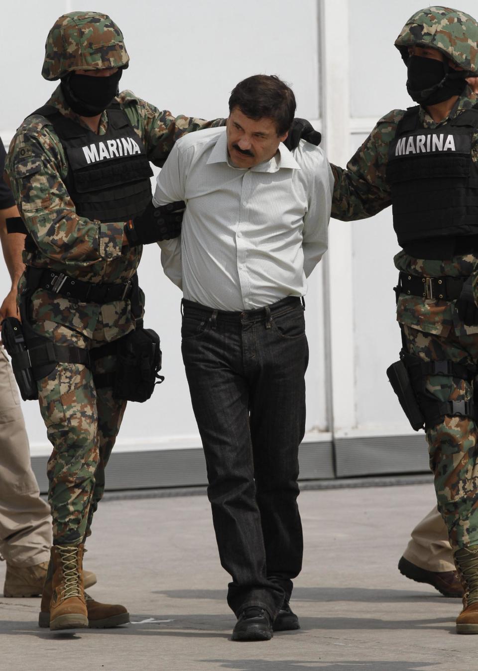 Joaquin "El Chapo" Guzman is escorted to a helicopter in handcuffs by Mexican navy marines at a navy hanger in Mexico City, Saturday, Feb. 22, 2014. A senior U.S. law enforcement official said Saturday, that Guzman, the head of Mexicoís Sinaloa Cartel, was captured alive overnight in the beach resort town of Mazatlan. Guzman faces multiple federal drug trafficking indictments in the U.S. and is on the Drug Enforcement Administrationís most-wanted list. (AP Photo/Marco Ugarte)