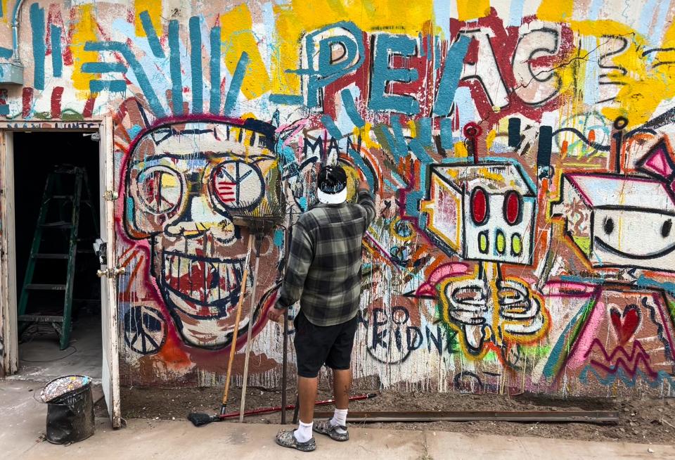 Diego "Robot" Martinez works on the exterior of the building that houses the art space he is renovating near Buddy's Beer Barn on the East Side. His exhibit, “Peace Love Dope Death,” was Sept. 9, 2022, to Sunday, Sept. 11, 2022.