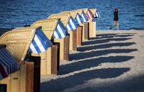 In this Thursday, May 21, 2020 photo, beach chairs cast long shadows on the beach at the Baltic Sea Luebeck-Travemuende, Germany. Germany's states, which determine their own coronavirus-related restrictions, have begun loosening lockdown rules to allow domestic tourists to return. (Daniel Bockwoldt/dpa via AP)