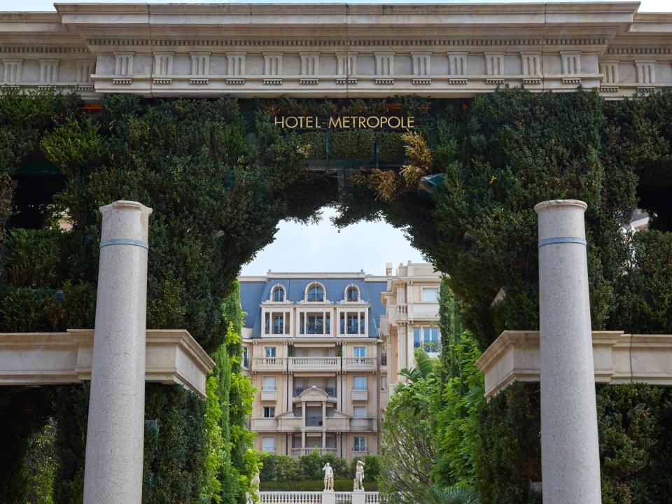 A hotel entrance as seen through an ivy covered arch with columns in Monaco.,