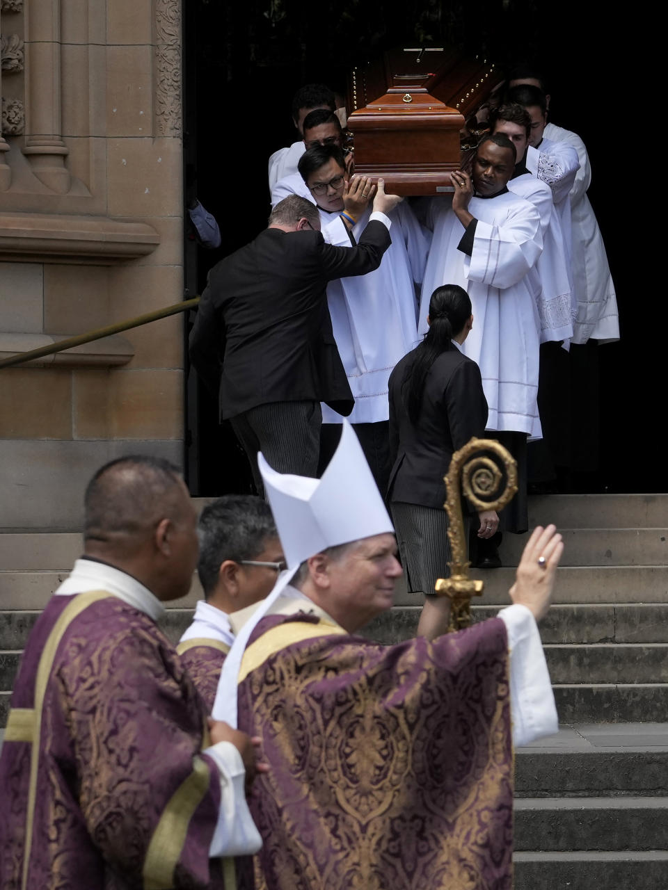 The coffin of Cardinal George Pell is carried out of St. Mary's Cathedral as Archbishop Anthony Fisher, bottom right, gestures following Pell's funeral in Sydney, Thursday, Feb. 2, 2023. Pell, who died last month at age 81, spent more than a year in prison before his sex abuse convictions were overturned in 2020. (AP Photo/Rick Rycroft)