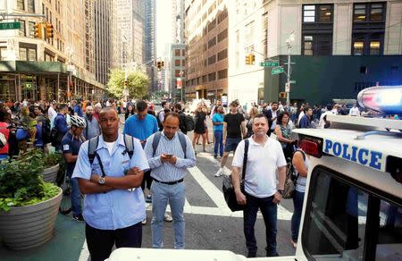 Commuters look on as police investigate the scene near an SUV in which a man suspected of causing a bomb scare barricaded himself, causing an hours-long standoff and the shutdown of a mid-Manhattan area in New York City, New York, U.S. July 21, 2016. REUTERS/Brendan McDermid