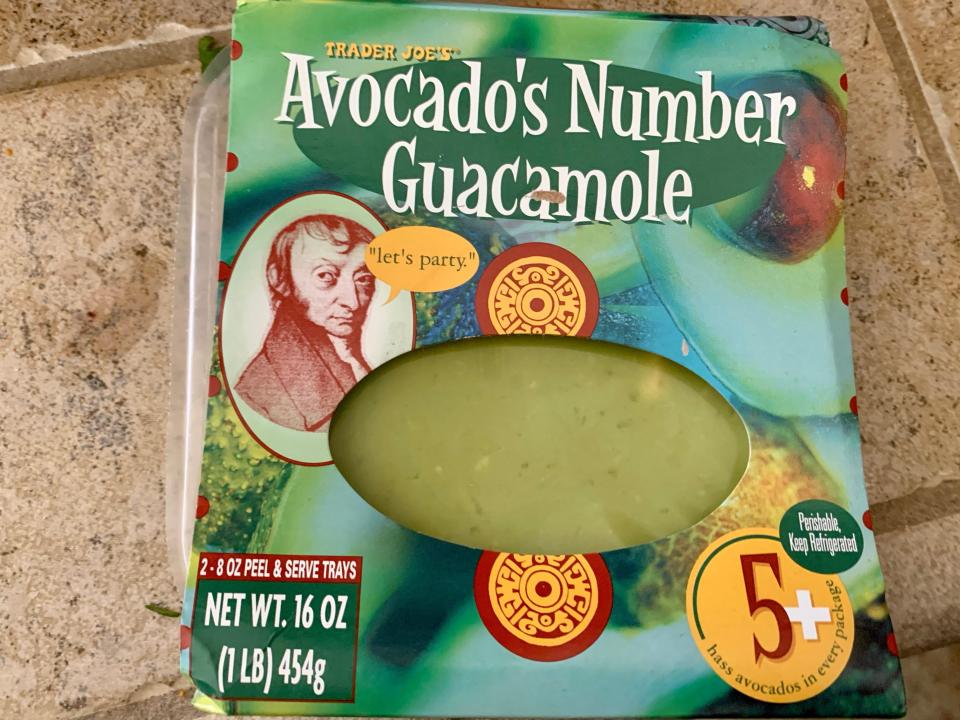 blue and green container of trader joe's avocado number guacamole on tile counter