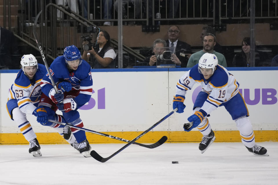 New York Rangers' Tyler Pitlick, center, competes for the puck with Buffalo Sabres Isak Rosen, left, and Peyton Krebs during the first period of an NHL hockey game, Monday, Nov. 27, 2023, in New York. (AP Photo/Seth Wenig)
