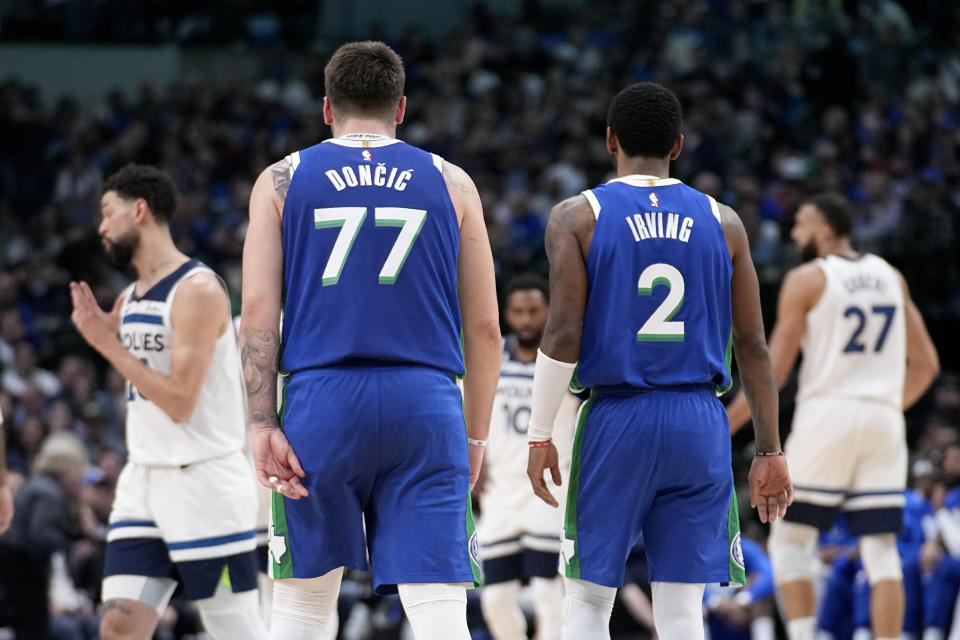 Dallas Mavericks' Luka Doncic (77) and Kyrie Irving (2) talk at mid court during the first half of an NBA basketball game against the Minnesota Timberwolves, Monday, Feb. 13, 2023, in Dallas. (AP Photo/Tony Gutierrez)