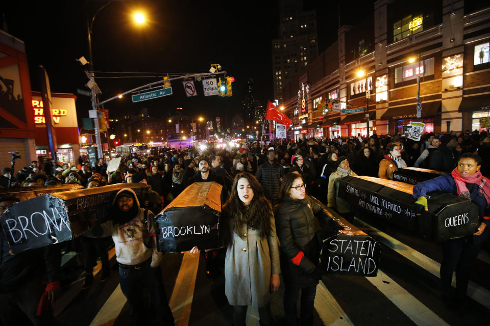 Protesters rallying against a grand jury's decision not to indict the police officer involved in the death of Eric Garner sing as they carry a collection of mock coffins bearing the names of victims of fatal police encounters at the intersection of Flatbush Avenue and Atlantic Avenue near the Barclays Center, Thursday, Dec. 4, 2014, in the Brooklyn borough of New York.  A grand jury cleared a white New York City police officer Wednesday in the videotaped chokehold death of Garner, an unarmed black man, who had been stopped on suspicion of selling loose, untaxed cigarettes. (AP Photo/Jason DeCrow)