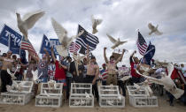 President Donald Trump supporters release doves during a march, in Huntington Beach, Calif., on Saturday, March 25, 2017. A scuffle later broke out on the Southern California beach between pro-Trump marchers and counter-protesters. (Mindy Schauer/The Orange County Register via AP)