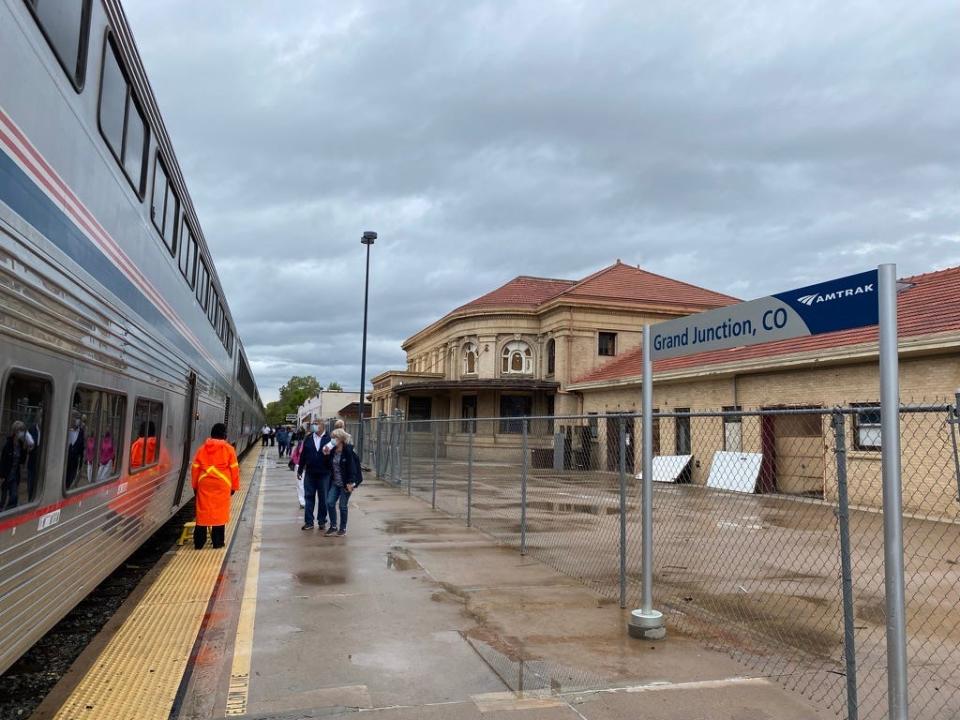 people standing outside an amtrak train at a station in colorado