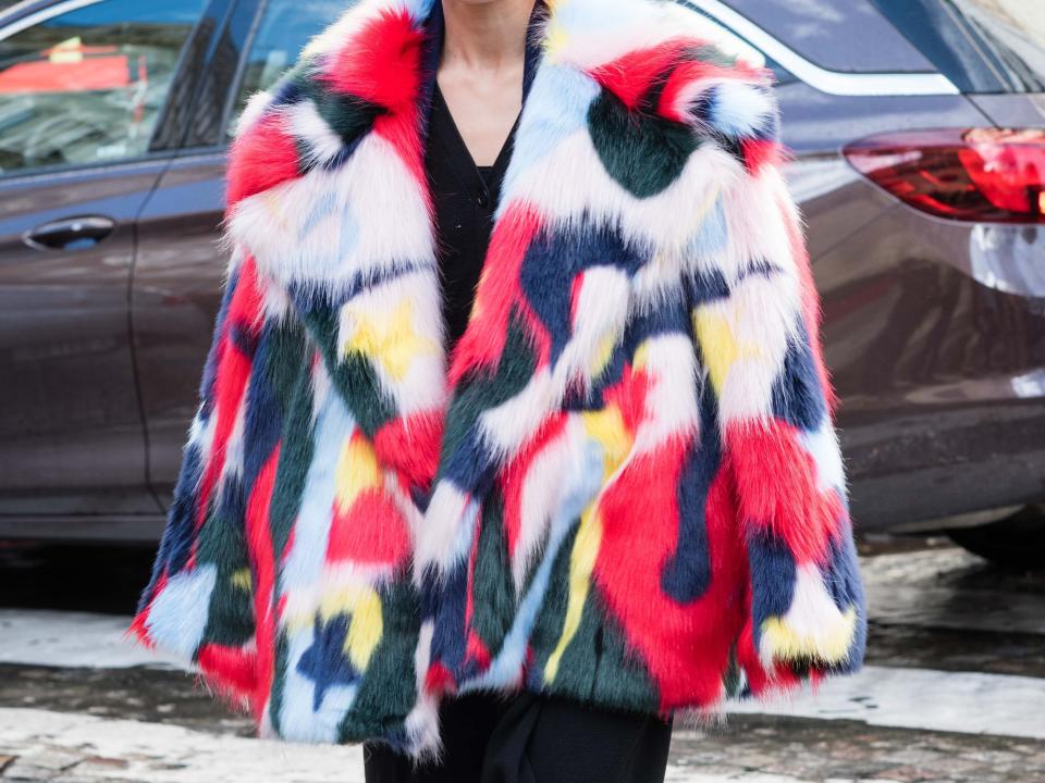 person wearing an oversized, colorful, faux fur jacket over a black outfit