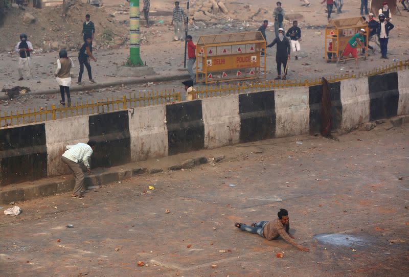 A man reacts as he falls during a clash between people supporting a new citizenship law and those opposing the law in New Delhi