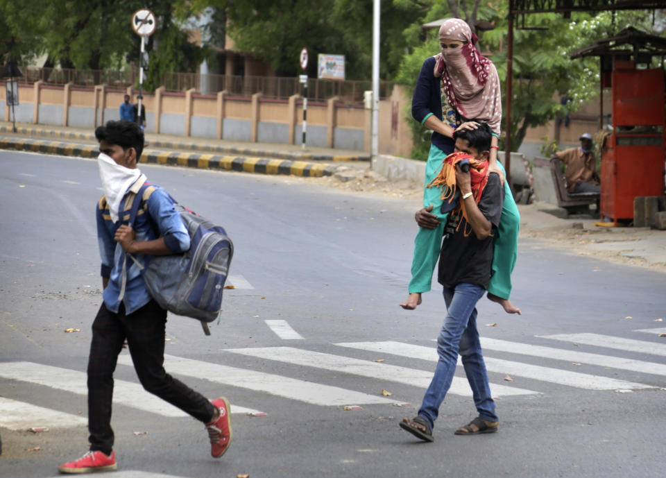 In this Thursday, March 26, 2020, file photo, a migrant worker Ramesh Meena from neighboring state of Rajasthan carries her wife Ramila Meena, who fractured her leg, on his shoulder, as they leave for their village after the city comes under lock down as a precautionary measure against COVID-19 in Ahmedabad, India. Over the past week, India’s migrant workers - the mainstay of the country’s labor force - spilled out of big cities that have been shuttered due to the coronavirus and returned to their villages, sparking fears that the virus could spread to the countryside. It was an exodus unlike anything seen in India since the 1947 Partition, when British colothe subcontinent, with the 21-day lockdown leaving millions of migrants with no choice but to return to their home villages. (AP Photo/Ajit Solanki, File)