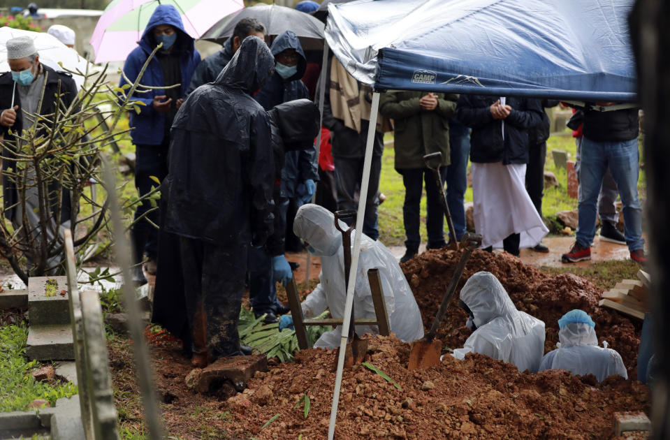 Undertakers wearing personal protective equipment exit the grave of Shaykh Seraj Hassan Hendricks during the funeral at the Mowbray cemetery in Cape Town, South Africa, Friday July 10, 2020. Hendricks who died of COVID-19 was the resident sheikh at the Azzawia Institute. (AP Photo/Nardus Engelbrecht)