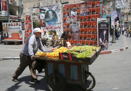 A vendor pushes his cart past pictures of Palestinian prisoners on hunger strike in Israeli jails, in the West Bank city of Nablus May 9, 2017. REUTERS/Abed Omar Qusini
