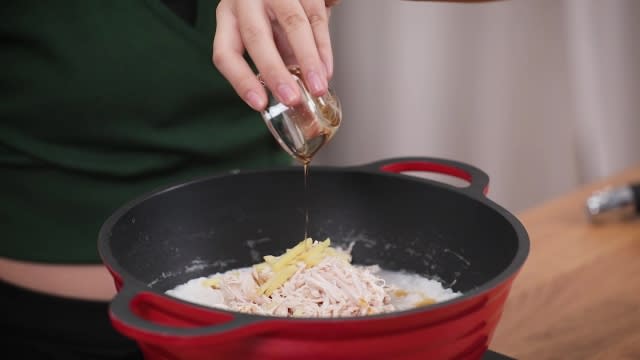 Adding sesame oil to cooking chicken porridge in pot