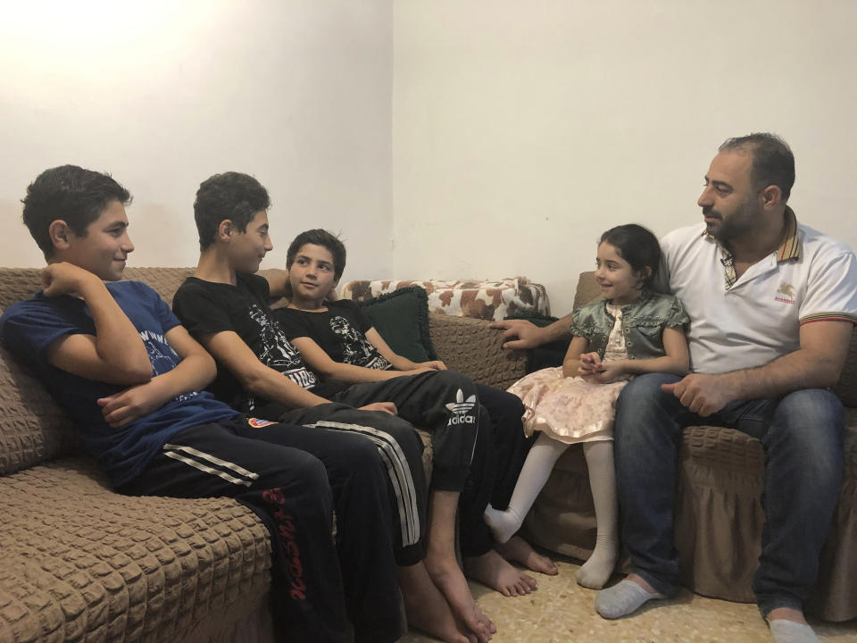 In this Sunday, Sept. 1, 2019 photo, Syrian refugee Zahir Hamshari sits with his children in his rented apartment in east Amman, Jordan. Seven years after fleeing the civil war in his homeland, Hamshari’s life is filled with questions and doubts: How to pay the rent? How to cover the electricity bill? How to afford even basic staples like bread and bottled water? But one thing is crystal clear for him. Like many Syrian refugees, he cannot envision returning to his war-torn country. (AP Photo/Omar Akour)