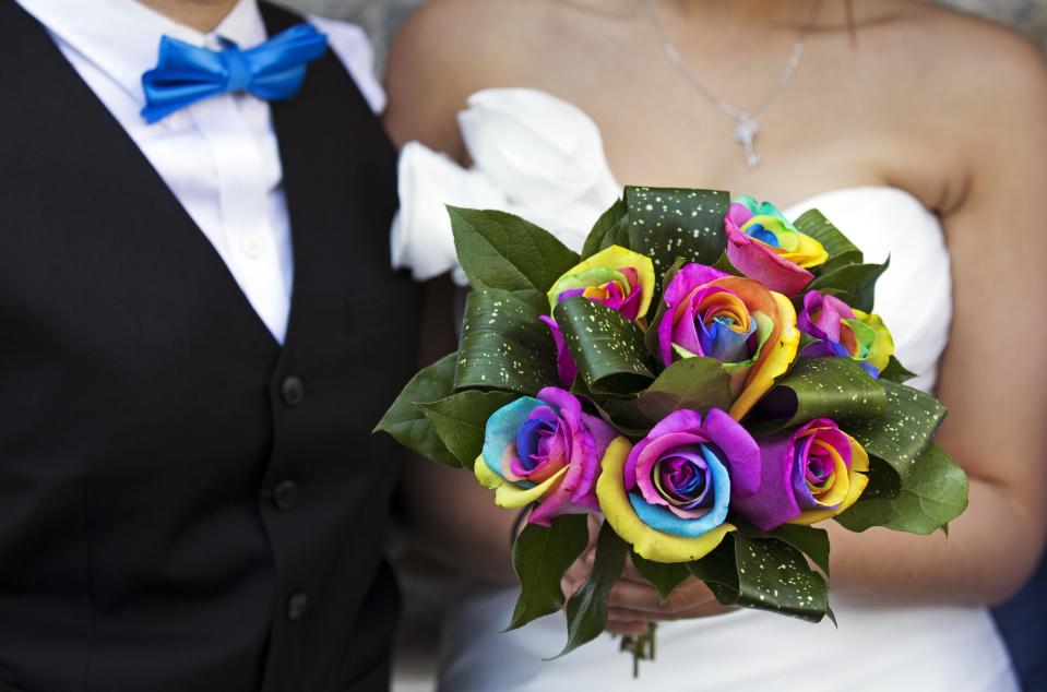 Lee stands next to her partner Chang Ho holding a rainbow-coloured bouquet of flowers, before they take part in "Celebration of Love" at Casa Loma in Toronto