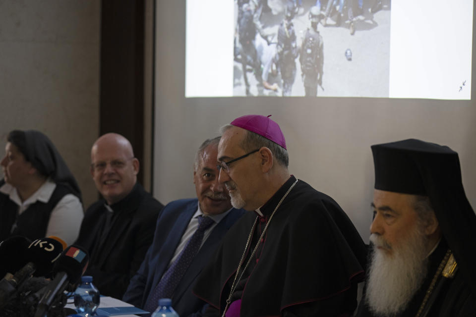 The Latin Patriarch of Jerusalem Pierbattista Pizzaballa, center, speaks with Jamil Koussa, General Director of St. Joseph's Hospital, beneath an image of Israeli police in riot gear during the funeral of slain Al Jazeera correspondent Shireen Abu Akleh on Friday, during a press conference about police violence against pallbearers at the funeral, in east Jerusalem, Monday, May 16, 2022. Pizzaballa, the top Catholic clergyman in the Holy Land, said Israel's police attack on mourners during a funeral for Abu Akleh was a violation of human rights and disrespected the Catholic Church. (AP Photo/ Maya Alleruzzo)