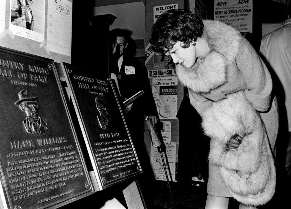 Country singer Patsy Cline admires plaques honoring the Country Music Hall of Fame's two newest members, Hank Williams Sr. and Fred Rose.