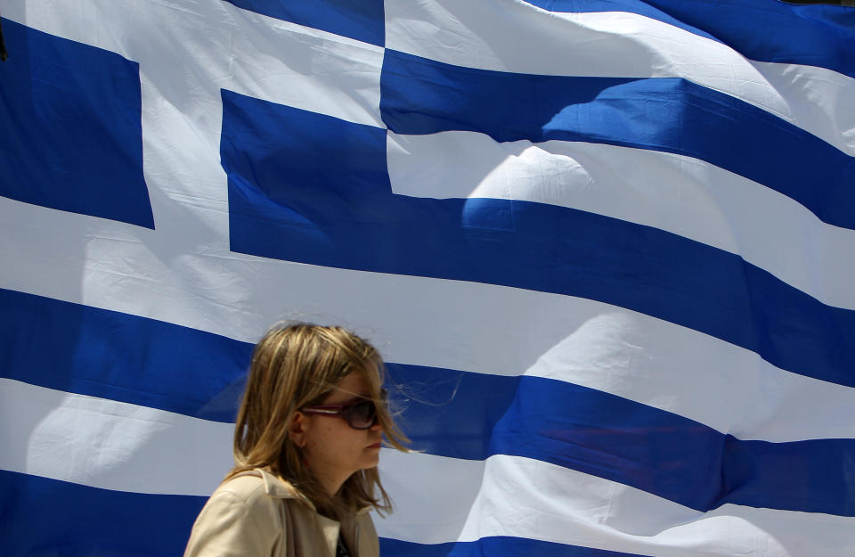 A woman passes in front of a Geek flag in Athens, Friday, April 20, 2012. Polls indicate that Greece's majority Socialists are trailing their main conservative rivals by up to 7 percentage points nearly two weeks before crucial national elections. Voting is scheduled for Sunday, May 6. (AP Photo/Thanassis Stavrakis)