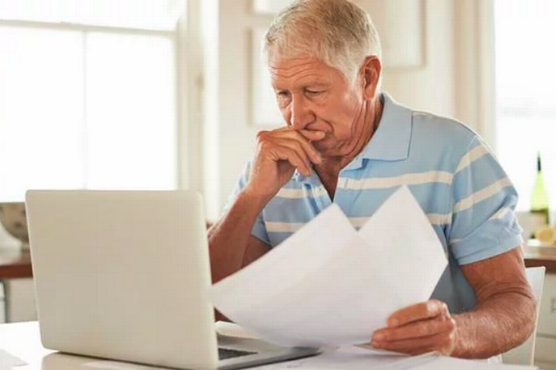 An older man is studying a form in front of him