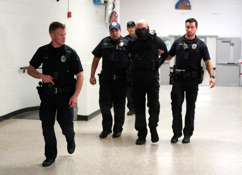 Savannah Police officers escort the role player shooter out in handcuffs during an active shooter drill at the STEM Academy at Bartlett.