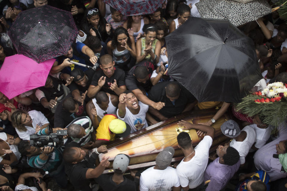 Familiares y amigos de Douglas Rafael da Silva Pereira rodean su ataúd durante el funeral en Río de Janeiro, Brasil, el jueves 24 de abril de 2014. Una protesta siguió al entierro de Pereira, cuya muerte a tiros provocó enfrentamientos el martes por la noche entre la policía y los vecinos de la favela Pavao-Pavaozinho. (Foto AP/Felipe Dana)